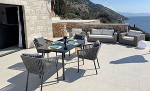 Esstisch und Sonnenschirme im Freien auf der Terrasse der luxuriösen Poolvilla in Kroatien mit Meerblick