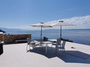 Outdoor dining table and parasols on the terrace of luxury Croatia pool villa with sea view