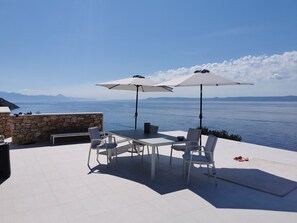 Esstisch und Sonnenschirme im Freien auf der Terrasse der luxuriösen Kroatien-Poolvilla mit Meerblick