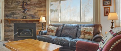 Living room with an abundance of natural light, brown leather couch and a red fabric chair