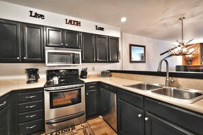 Kitchen includes beautiful stainless steel appliances, black cabinets and white countertops