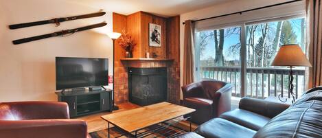 Living room features comfortable seating for 5, flat screen TV and a cozy gas fire place