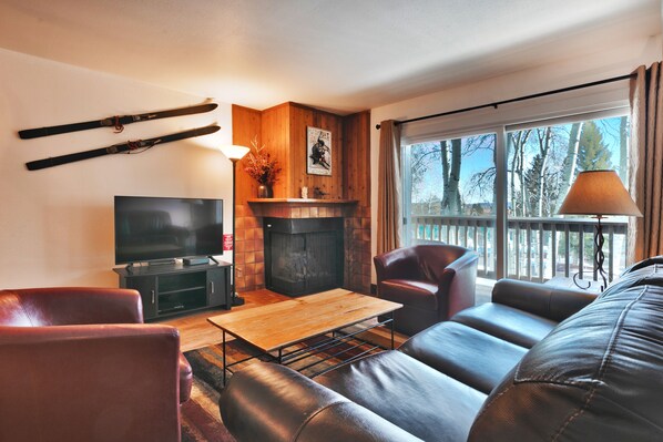 Living room features comfortable seating for 5, flat screen TV and a cozy gas fire place