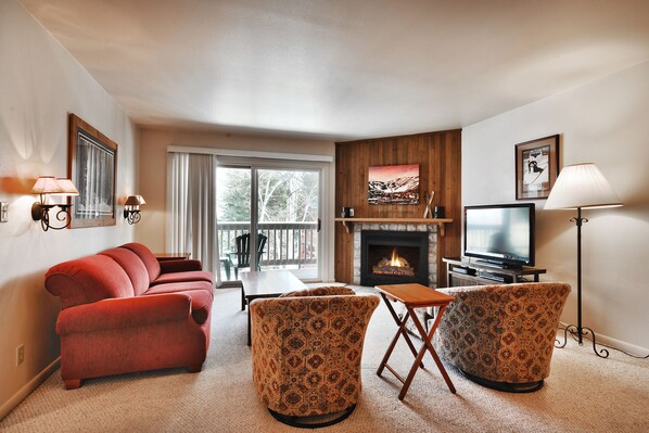 Living room features comfortable seating on a red couch and two barrel chairs