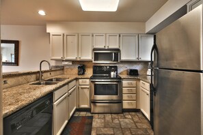 The kitchen includes stainless steel appliances, white cabinets and beautiful granite countertops