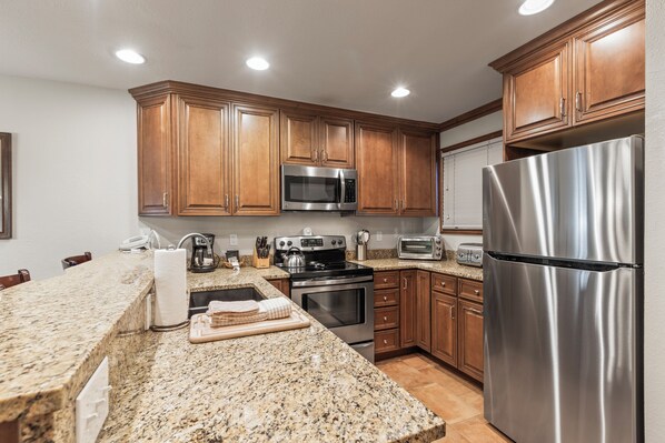 Snow Flower 135's kitchen with medium colored wood cabinets, granite counters, and stainless steel appliances.