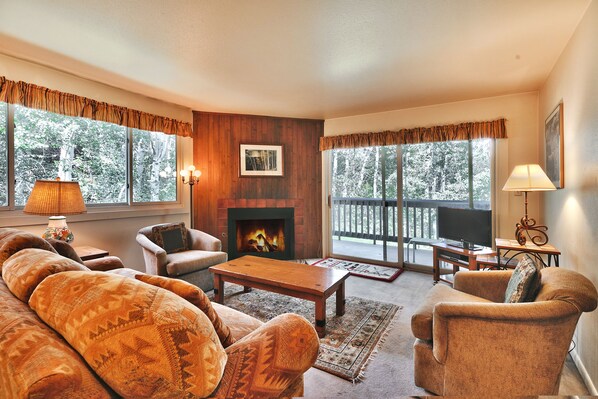 Cozy living room with wood accents, gas fireplace, and sliding glass doors to private patio