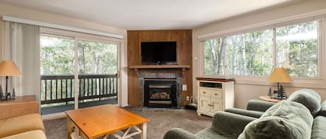 Living room features a gas fireplace, flat screen TV and access to the private patio through sliding glass doors