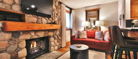 Living room features a gas burning fireplace with rock surround and large flat screen TV