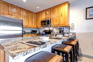 Snow Flower 30 offers an open concept kitchen with wood cabinets and breakfast bar with seating for four guests.