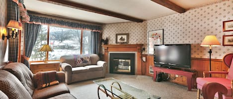 Living room features a flat screen TV, gas fireplace, flowered wallpaper
