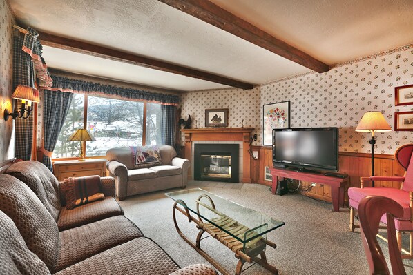 Living room features a flat screen TV, gas fireplace, flowered wallpaper