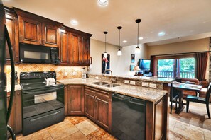 The kitchen has beautiful granite countertops and dark wood cabinets