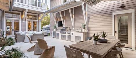 Incredible courtyard lounge with summer kitchen, outdoor sofa, outdoor dining, and flat screen TV.