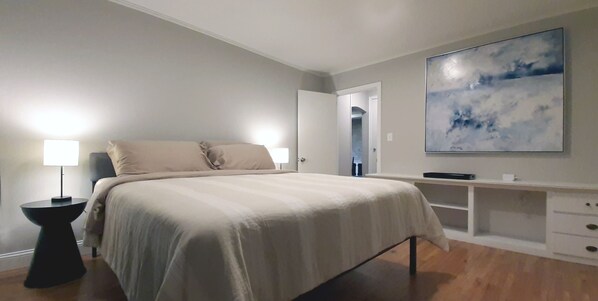 King size bed with memory foam mattress and smart TV in bedroom.