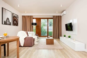 A bright open-plan living area that includes a comfortable sofa and a coffee table. The wooden floors and decor create a warm and inviting ambiance.