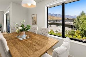 Open plan dining area with large table for six people; mountain views