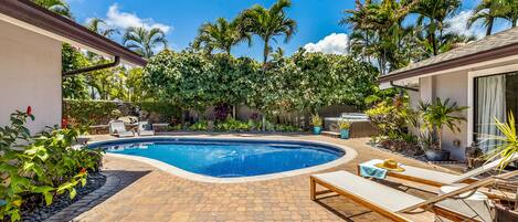 Tranquil pool deck with a jacuzzi and waterfall