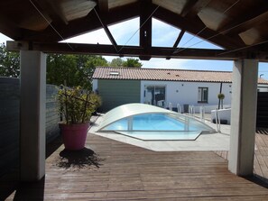 Accès au logement situé à l'arrière de la piscine, entrée par la baie vitrée.