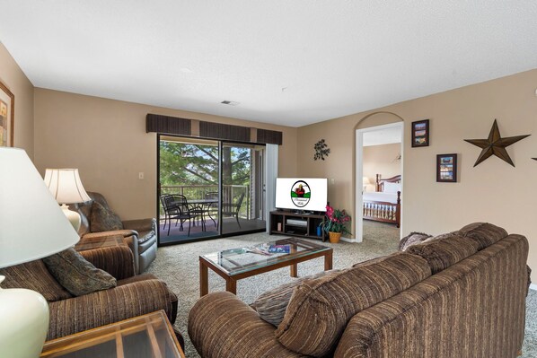 Living area features a queen sleeper sofa, cable TV, a new smart TV, DVD player, VCR, and direct balcony access!