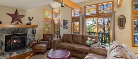 Welcome to the Haystack Retreat! Cozy living room with stone fireplace, big wall of windows with golf course views, and smart tv.