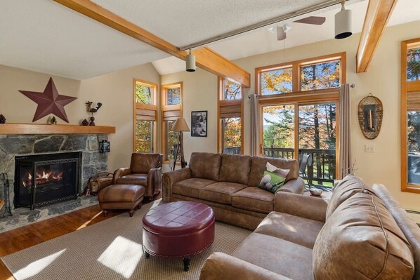 Welcome to the Haystack Retreat! Cozy living room with stone fireplace, big wall of windows with golf course views, and smart tv.