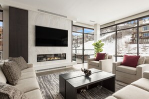 Striking living room with window walls, quartz feature fireplace wall and large screen TV