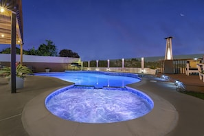 The pool and jacuzzi glow with soothing color-changing LED lights