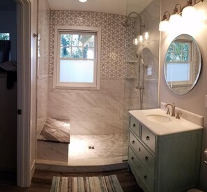 Beautiful walk in shower has on demand hot water and rain head fixture.