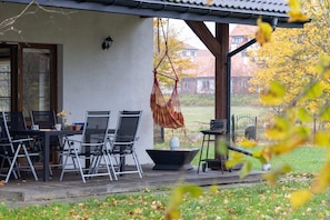 A porch that invites you to relax in a pleasant setting. Garden furniture and a swing provide relaxation.