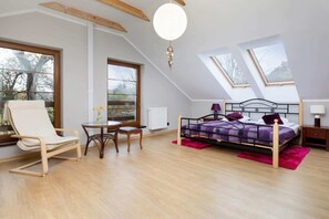 A spacious bedroom with a stylish double bed above which there are skylights. A rocking chair and coffee table can be seen to the right of the photo.