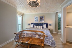 - Cozy bedroom with soft colors & wood accents feels calm & inviting for any stay - Large windows & glass door bring in fresh light & glimpses of the ocean beyond - Simple bench at the foot of the bed adds charm, comfort, & extra space to settle in