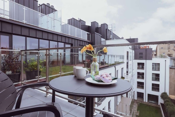 Furnished balcony with green surroundings.