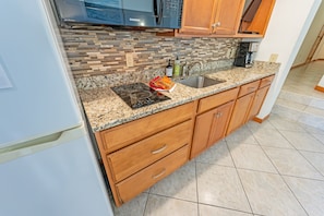 - Modern kitchenette with polished granite countertops and a chic tile backsplash - Equipped with a stovetop, microwave, sink, and coffee maker for your cooking needs - Great for preparing quick meals or enjoying your morning routine with ease