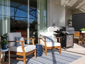 Outdoor area featuring plush cushioned chairs and a barbecue grill