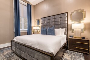 Spacious master bedroom with king-size bed, ensuite bathroom, and designer built-in closets. Equipped with lamps, hangers, luggage racks, alarm clock, white noise machine, and a 50'' Samsung Smart 4K TV with streaming and DIRECTV Entertainment.