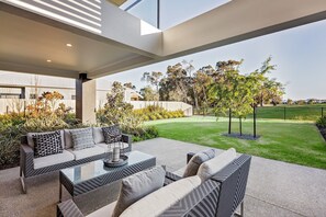 From the living area, you can access an undercover patio and lounge suite overlooking the grassy yard and course.