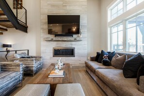 Living Room with High ceilings, Wall of Windows, a Smart TV, Wood Flooring Throughout