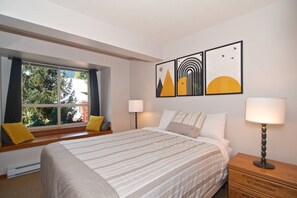 Master bedroom with Queen bed, window seat and wall mounted TV