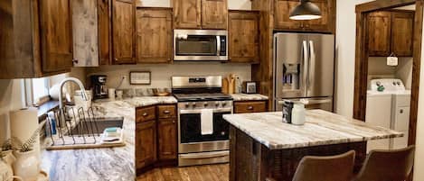 Live edge granite and gorgeous cabinets. Stocked kitchen. 