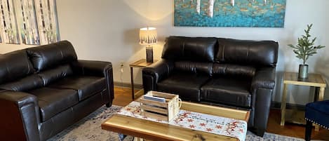 Spacious living room features leather couches, fireplace, and a TV
