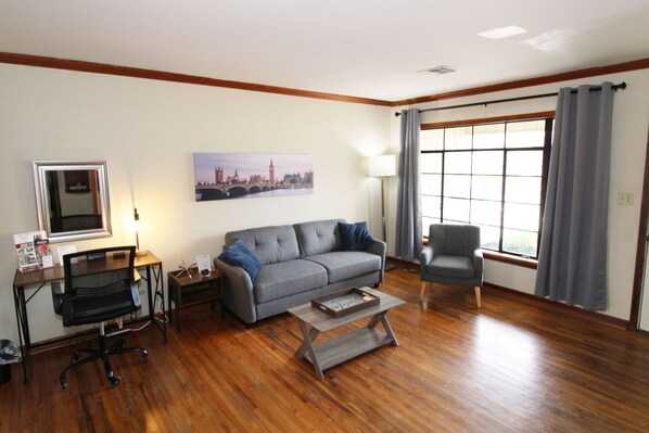 Livingroom has comfy couch and chair as well as a desk for work or a vanity