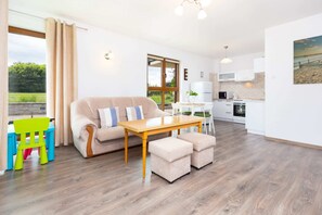 A combined living and dining space with modern furniture, a small play area for children, and bright natural lighting.
