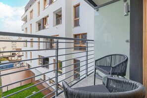 A view from a balcony overlooking a modern apartment complex, with outdoor chairs and greenery adding to the relaxing outdoor ambiance.