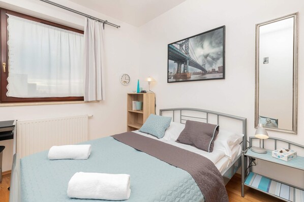 A bedroom with a neatly made bed, bedside tables, and a framed picture on the wall. The space is cozy and functional.