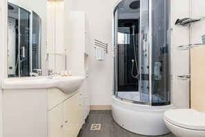 A modern bathroom featuring a glass shower cabin, white fixtures, and a clean, practical layout.