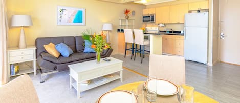 Living room with open kitchen, dining table, reclining sleeper sofa and central AC