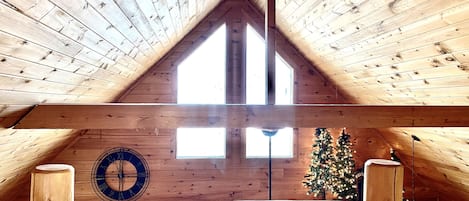 Cathedral ceilings frame windows allowing glowing natural light and night sky.