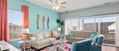 Open living room with large window and sliding door to balcony with seating.