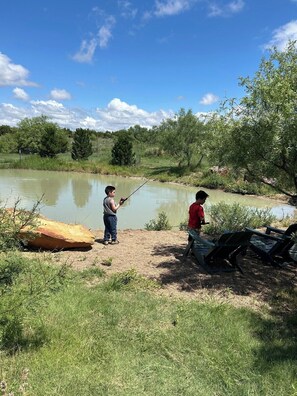 Stocked fishing pond with poles on sight.